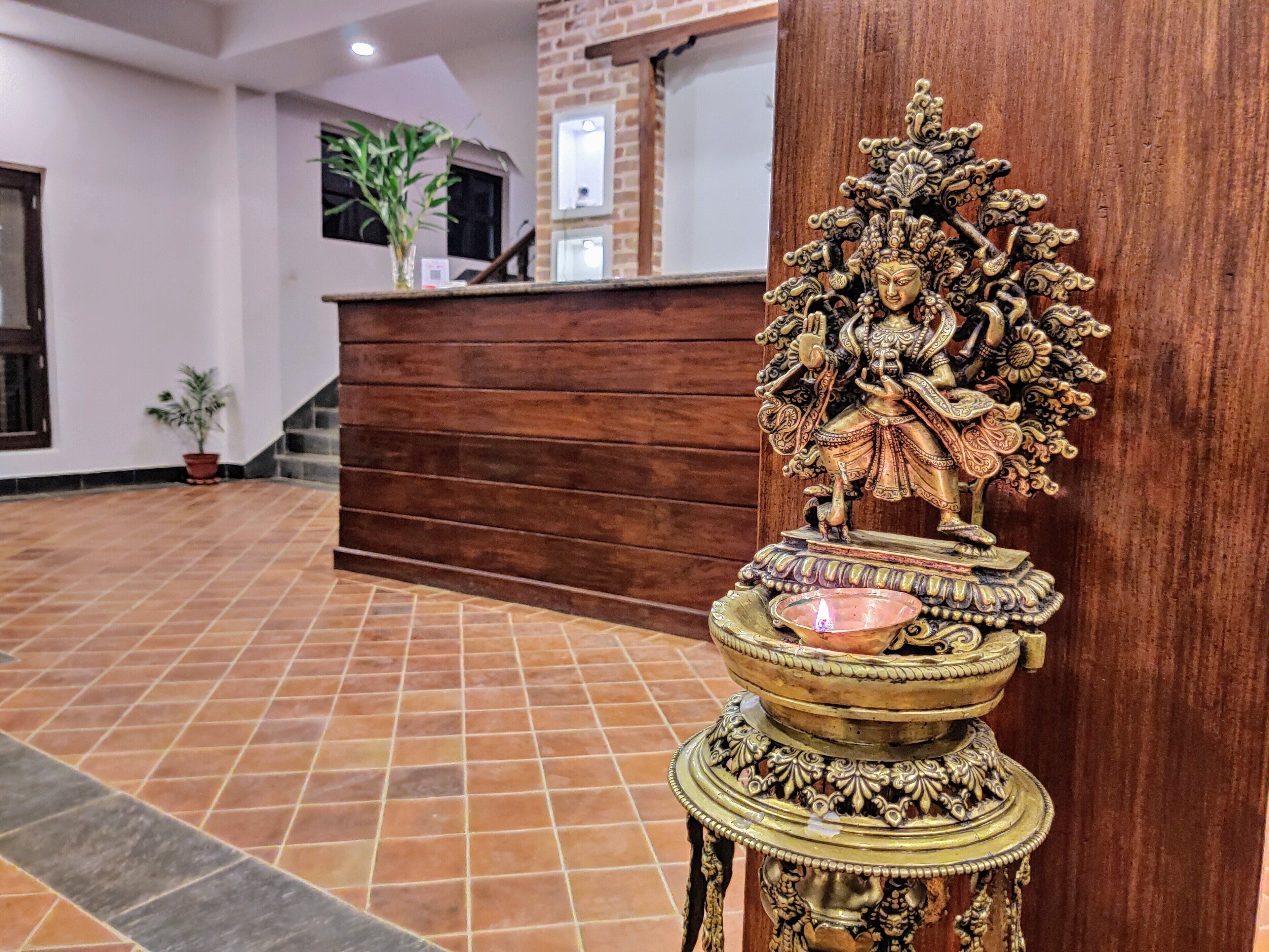 A reception area with a wooden reception desk, a decorative statue, and a tiled floor.