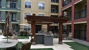 An outdoor patio area with a pergola, seating, and a grill station.