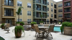 A courtyard with outdoor seating, a pool, and multi-story buildings with balconies.