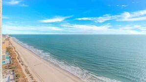 A beach with a clear sky, a sandy shore, and buildings along the coastline. - Palace 2102 (Myrtle Beach)