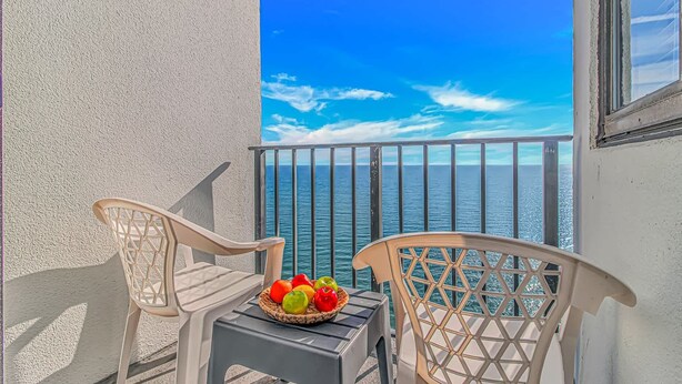 A balcony with two chairs and a table with a fruit basket, overlooking the sea. - Palace 2102 (Myrtle Beach)