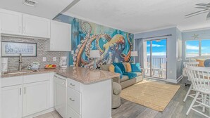A kitchen with white cabinets, a granite countertop, and a mural of an octopus. - Palace 2102 (Myrtle Beach)