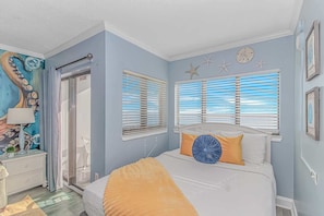 Un dormitorio con una cama, dos ventanas con persianas, una puerta y una pared decorada con estrellas de mar.