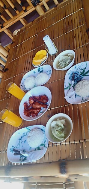 A table with various dishes including rice, chicken, and soup, along with glasses of juice. - The Orchids Private Villa (Boracay Island)