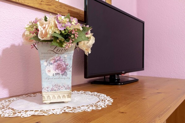 A desk with a vase of flowers, a computer monitor, and a doily. - Pensión Restaurante Chiki (Peniscola)