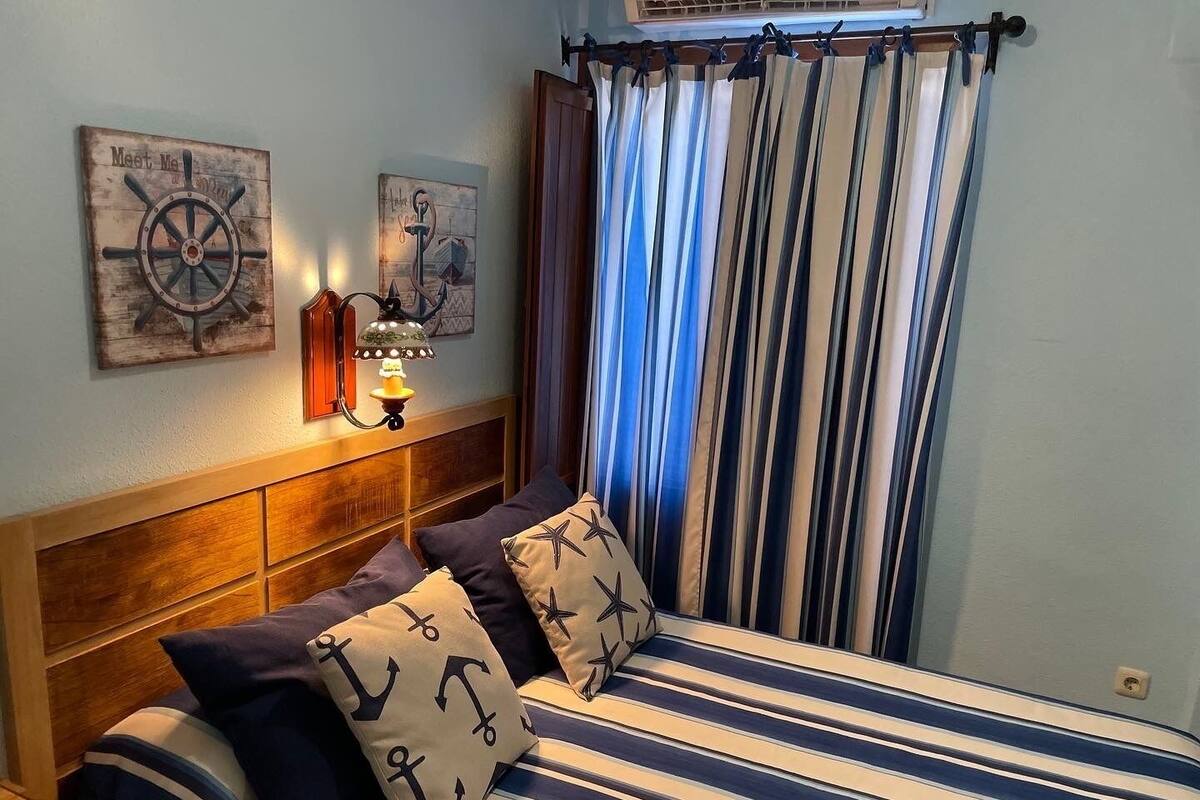 A bed with striped bedding, a headboard, and nautical-themed pillows.