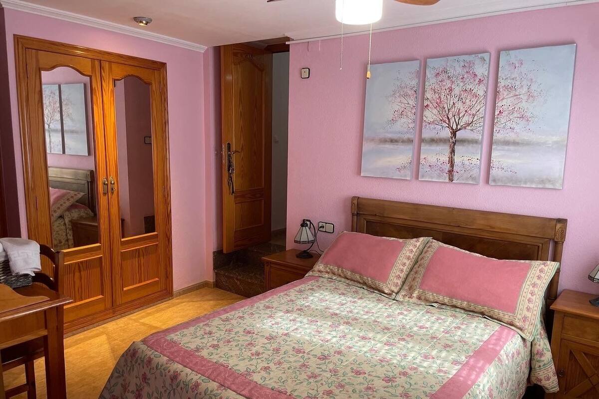 A bedroom with a wooden bed, a nightstand, a desk, and a wardrobe.