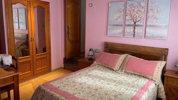 Un dormitorio con una cama de madera, una mesita de noche, un escritorio y un armario.