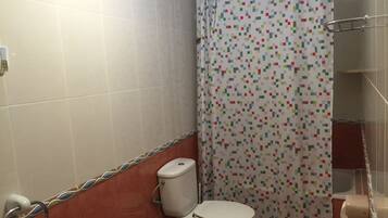 A bathroom with a toilet, bidet, and shower curtain.