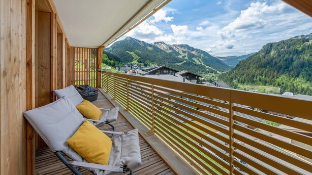 Una terraza de madera con vistas a un paisaje montañoso.
