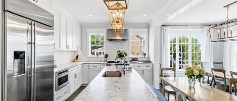 A modern kitchen with a central island, stainless steel appliances, and a pendant light fixture.