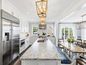 A modern kitchen with a central island, stainless steel appliances, and a pendant light fixture.