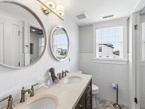 Une salle de bain avec deux lavabos, un grand miroir et une fenêtre.