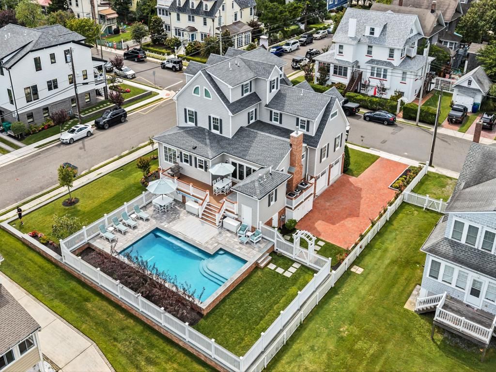 Una propiedad residencial con piscina, un porche cubierto y un patio trasero cercado.