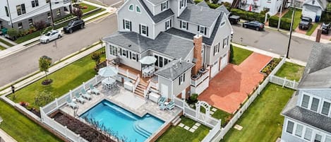 Una propiedad residencial con piscina, un porche cubierto y un patio trasero cercado.