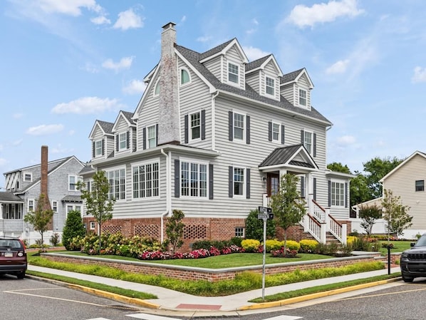 A two-story house with a brick foundation, white siding, and a chimney.