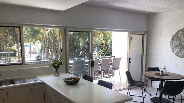 Una cocina moderna con un ventanal grande, un comedor con sillas y una mesita.