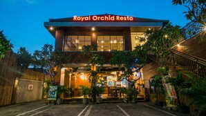 The exterior of Royal Orchid Resto with a well-lit entrance, potted plants, and a staircase leading to the entrance. - Royal Orchid Lodge (Nusa Dua)