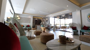 A spacious living area with wicker furniture, a marble table, and a large window providing natural light. - Royal Orchid Lodge (Nusa Dua)