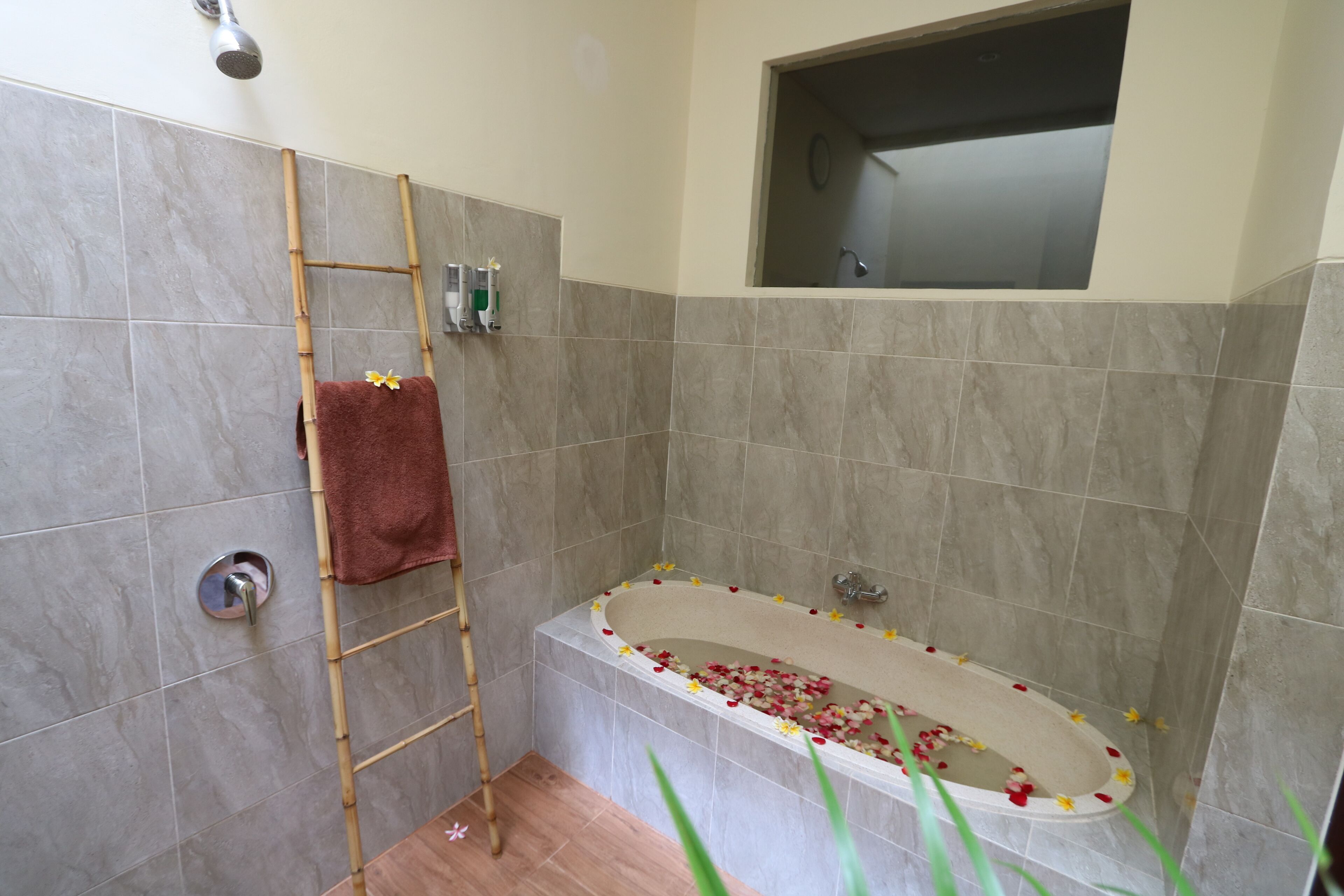 Een badkamer met een bad, douche en een raam.