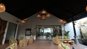 A spacious lobby with wicker furniture, a glass entrance, and a ceiling with hanging lights. - Royal Orchid Lodge (Nusa Dua)