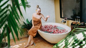 A woman in a towel by a large bathtub filled with water and flower petals. - Royal Orchid Lodge (Nusa Dua)