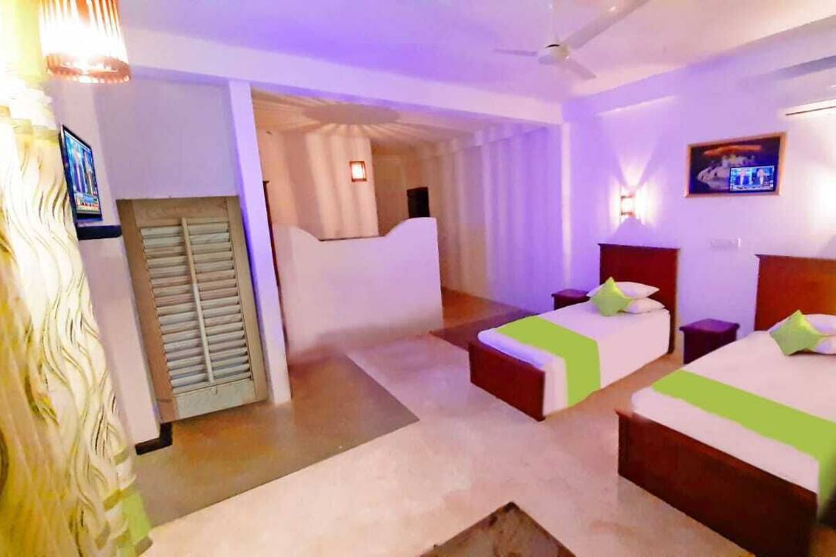 A hotel room with two beds, a television, and a ceiling fan.