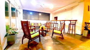 A spacious living area with multiple wooden chairs and tables, a large window, and a ceiling fan. - Akurala Beach Boutique Resort (Akurala)