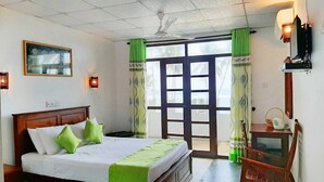 A hotel room with a bed, a desk, a chair, a television, and a window with curtains. - Akurala Beach Boutique Resort (Akurala)
