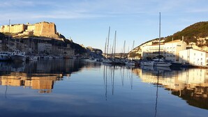A marina with boats docked, a historic castle on a hill, and a hotel building. - Villa Bonifacio 12p, swimming pool -1km from the port Preserved and exceptional environment (Bonifacio)