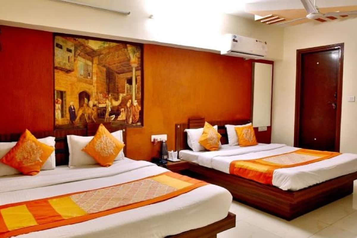A hotel room with two beds, a large painting on the wall, and an air conditioning unit.
