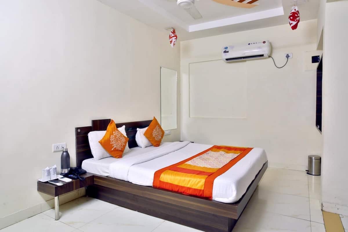 A hotel room with a bed, nightstand, and an air conditioning unit.