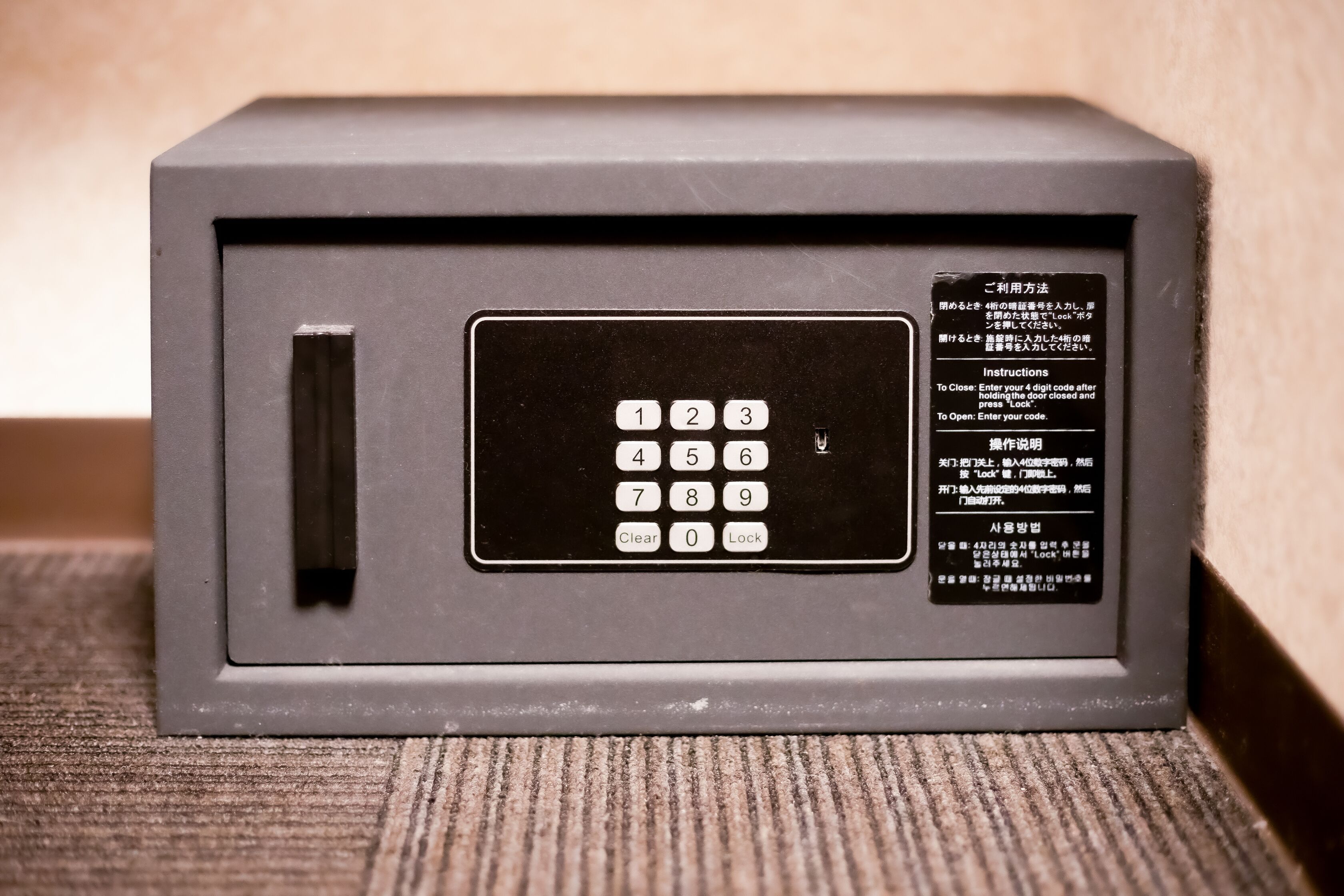 A gray, rectangular safe with a keypad and instructions in Japanese.