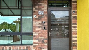 A building entrance with a brick facade, a glass door, and a bench outside. - Youge Homestay (Taitung)