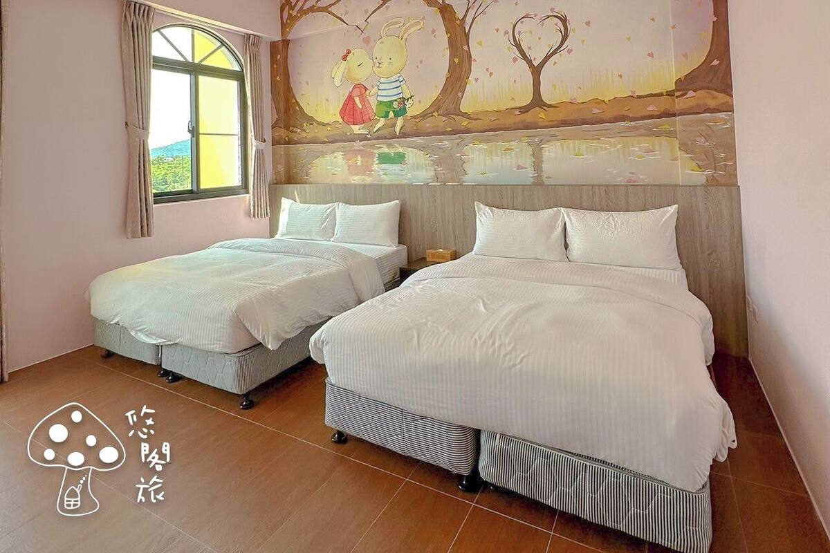 A bedroom with two single beds, a large mural on the wall, a ceiling light fixture, and a window with curtains.