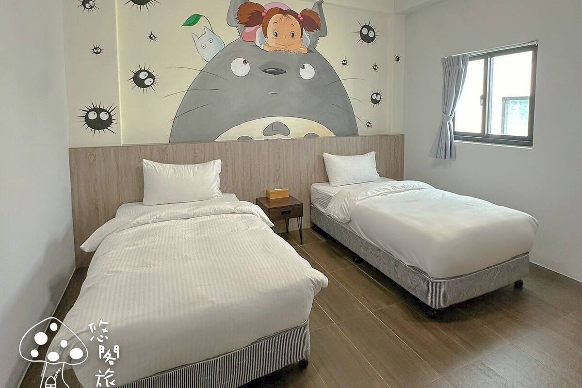 A hotel room with two beds, a large wall mural, a window with curtains, and a ceiling light fixture.