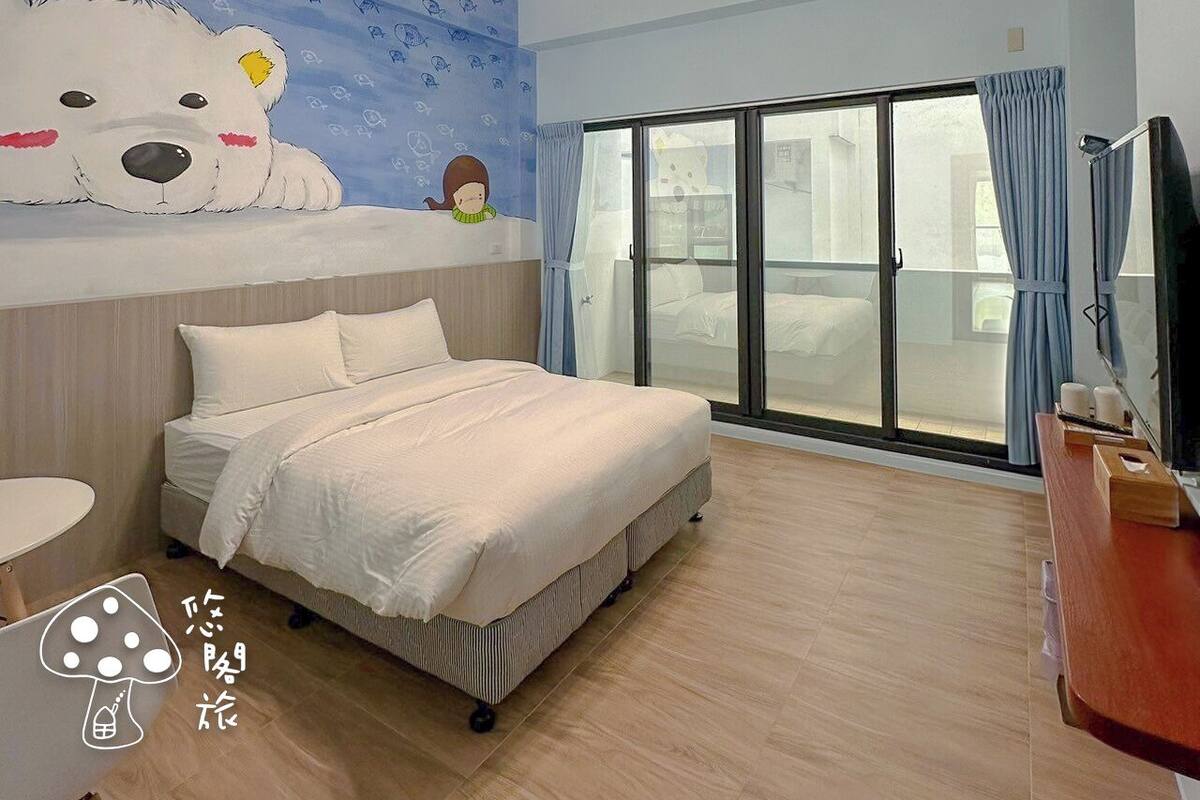 A bedroom with a bed, a large wall mural, a chandelier, and a sliding glass door leading to a balcony.