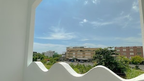 A view from a balcony with a curved white railing, overlooking a street with buildings and greenery. - Youge Homestay (Taitung)