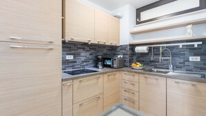A modern kitchen with light wood cabinets, a black tiled backsplash, and stainless steel appliances. - Right in the Porec center, near the beach,WiFi,air conditioning,garage, elevator (Porec)