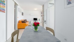 A modern living room with a grey dining table, orange sofa, and a TV in the background. - Right in the Porec center, near the beach,WiFi,air conditioning,garage, elevator (Porec)