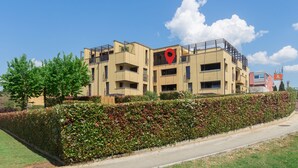 A multi-story residential building with balconies, a red location marker, and a well-maintained hedge along the sidewalk. - Right in the Porec center, near the beach,WiFi,air conditioning,garage, elevator (Porec)