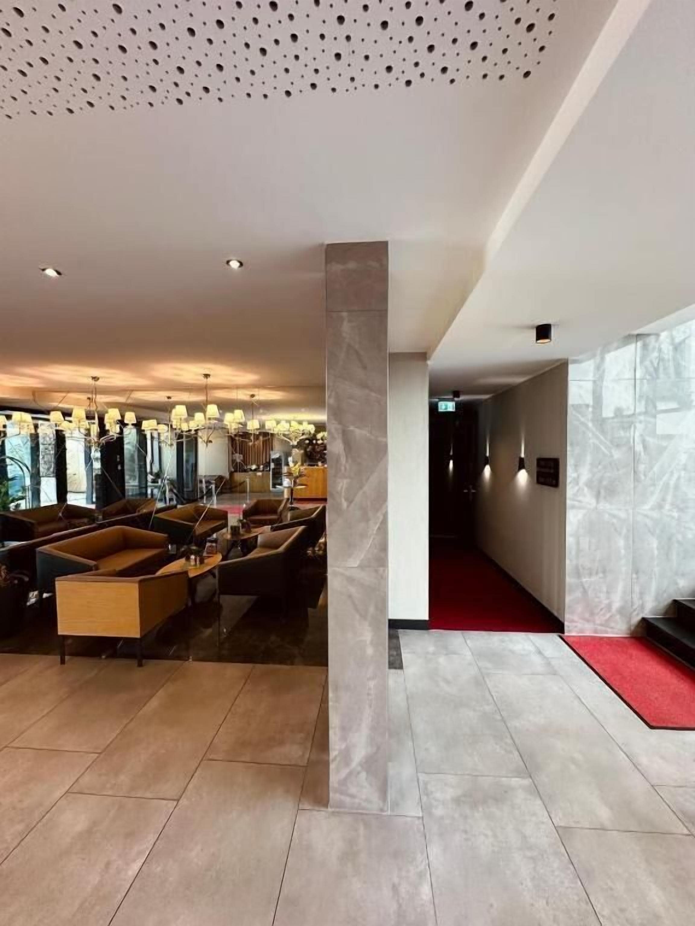 Un vestíbulo amplio con techo alto, una columna de mármol y una alfombra roja que conduce a una escalera.