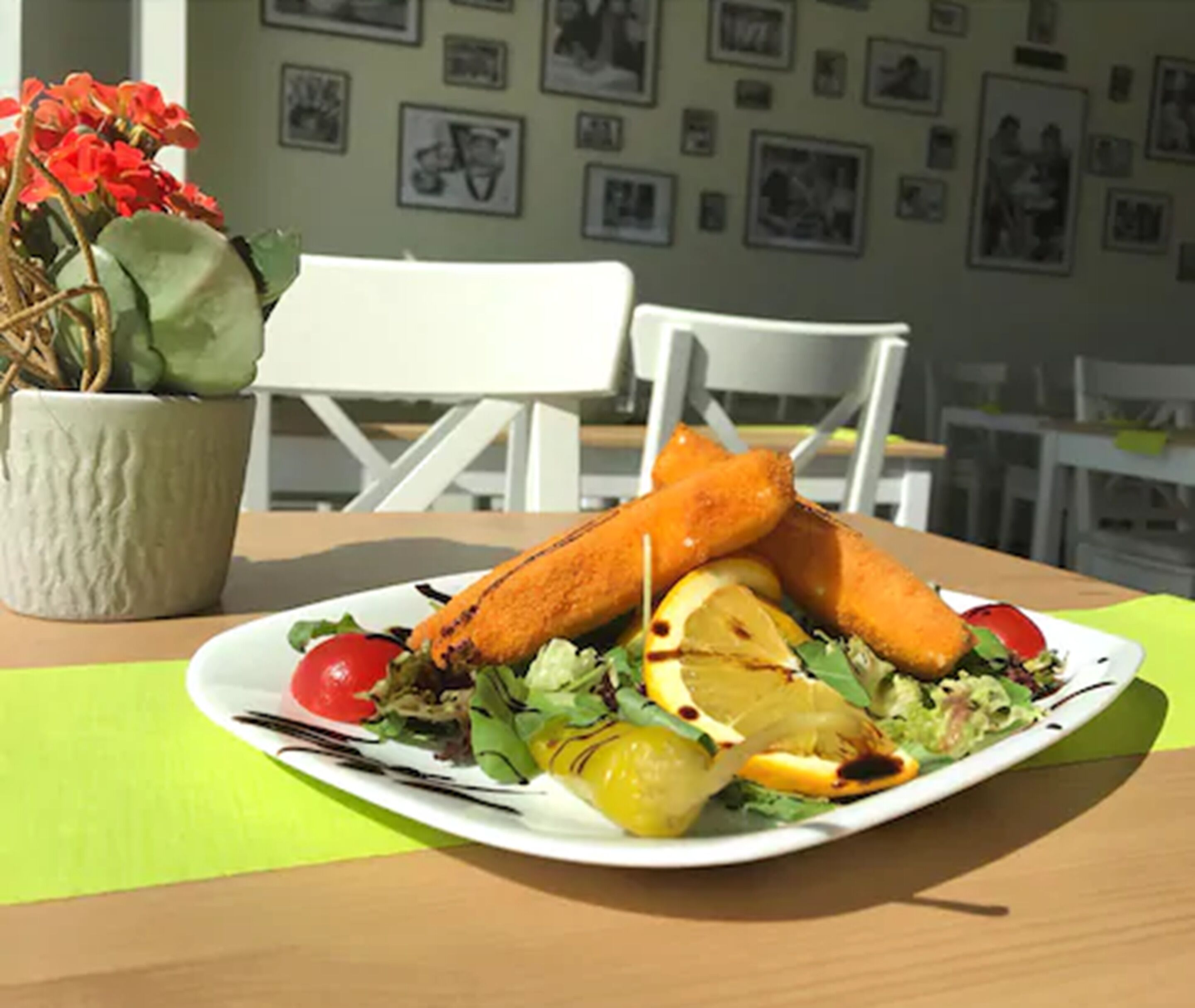 Un plato de comida con alimentos fritos, ensalada y rodajas de limón sobre una mesa con un camino de mesa verde.