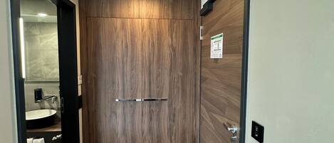 Un corridoio con una porta in legno, una bocchetta d'aerazione e un pavimento piastrellato.