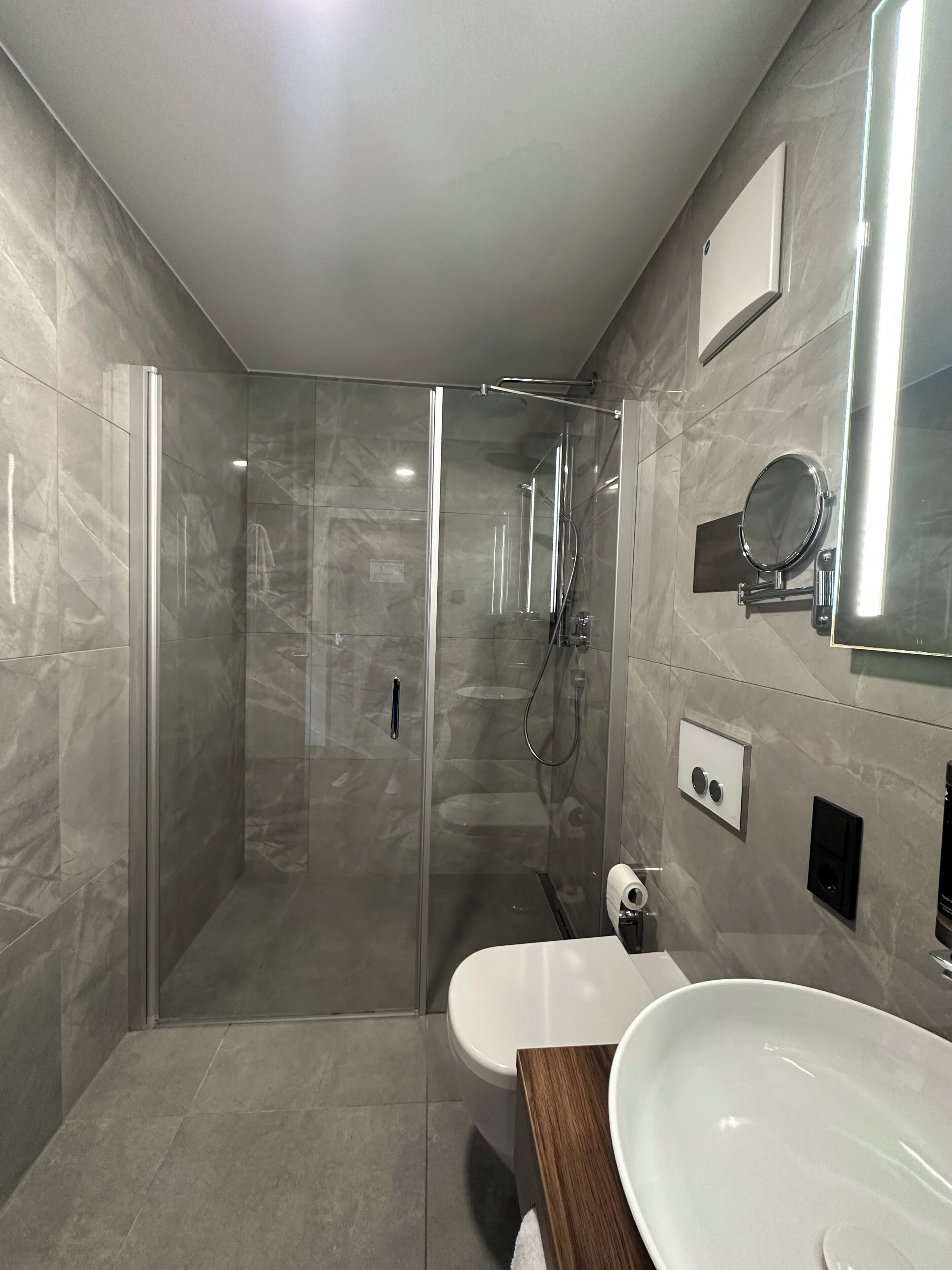 A modern bathroom with a glass-enclosed shower, a white sink, and a mirror.