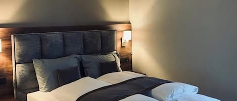 Un lit bien fait, avec une tête de lit, une table de chevet et un luminaire fixé au mur.