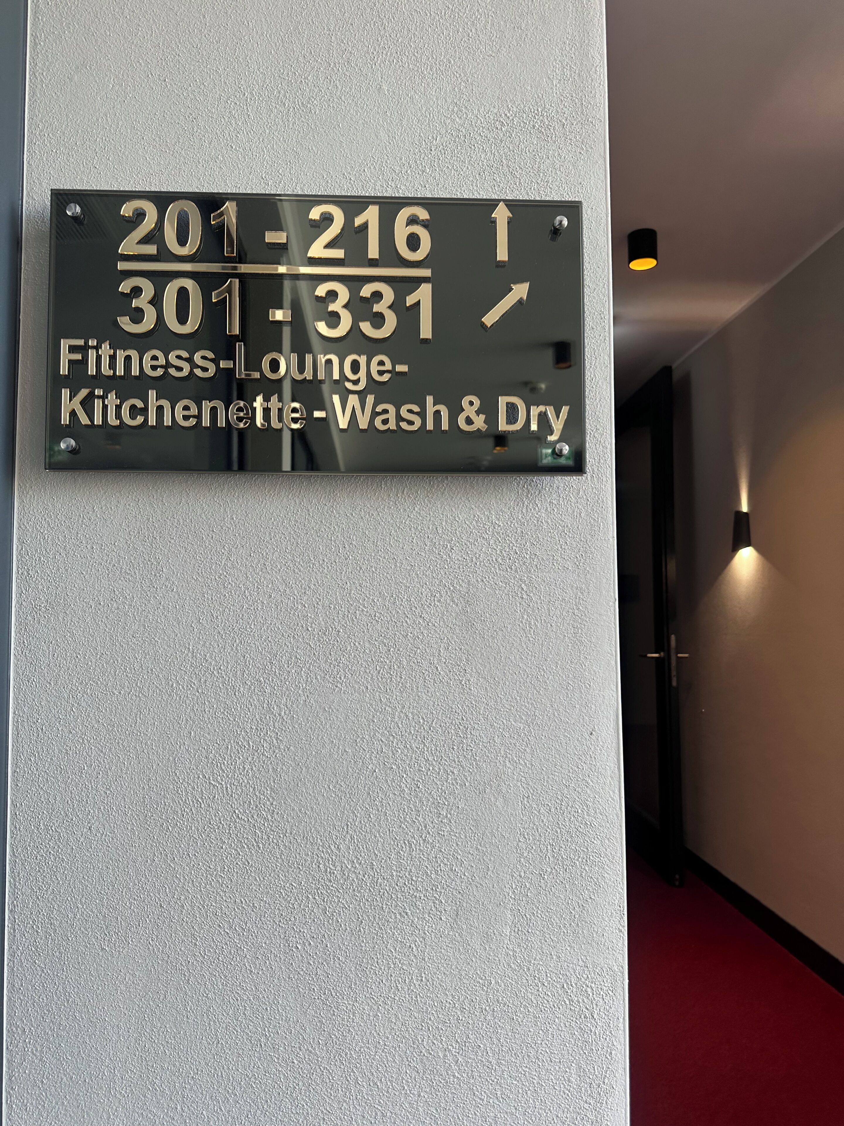 Un letrero con números de habitaciones y servicios, incluyendo un gimnasio, kitchenette y lavandería.