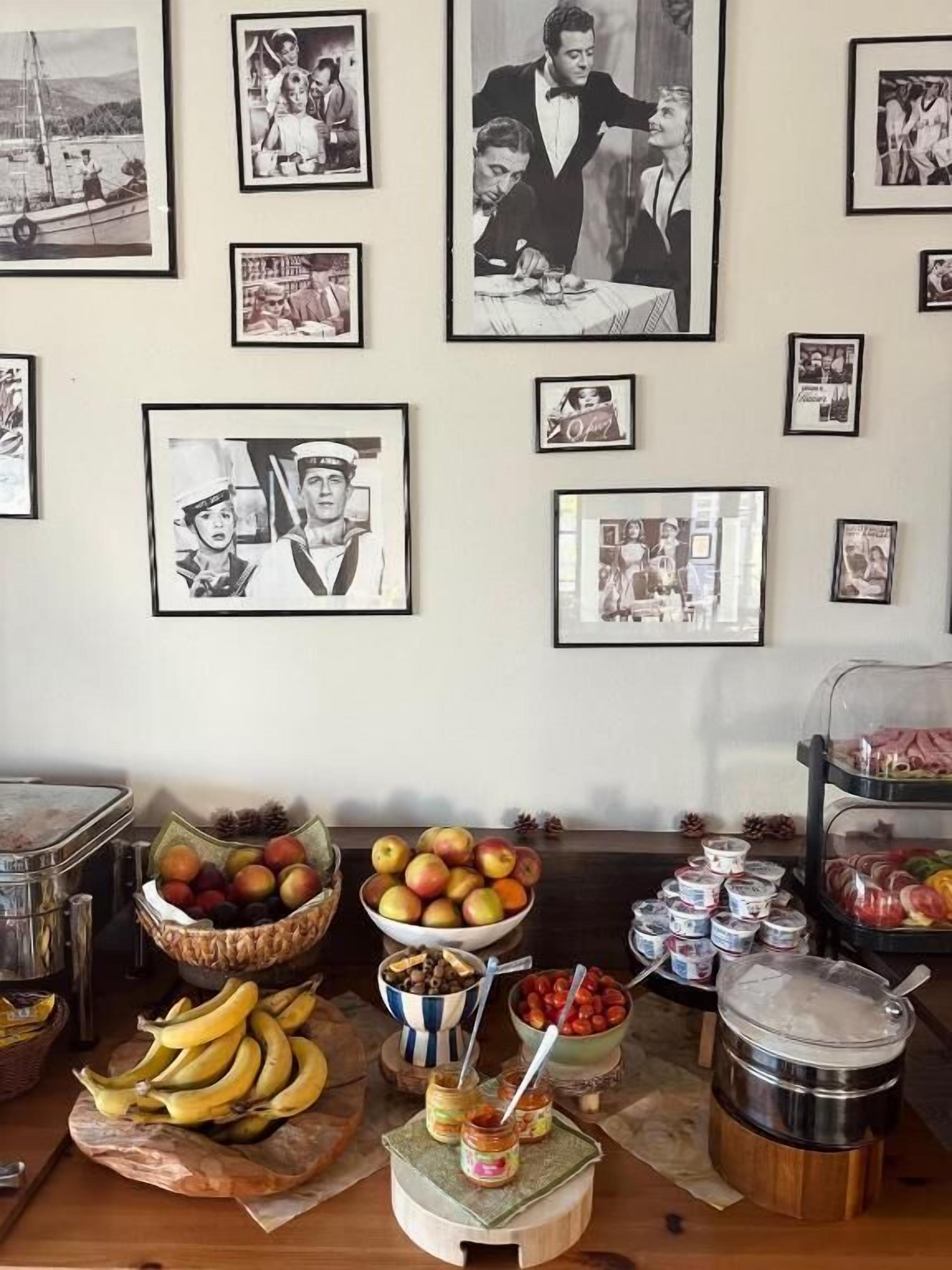 Een muur met ingelijste zwart-witfoto's en een tafel met verschillende soorten eten.