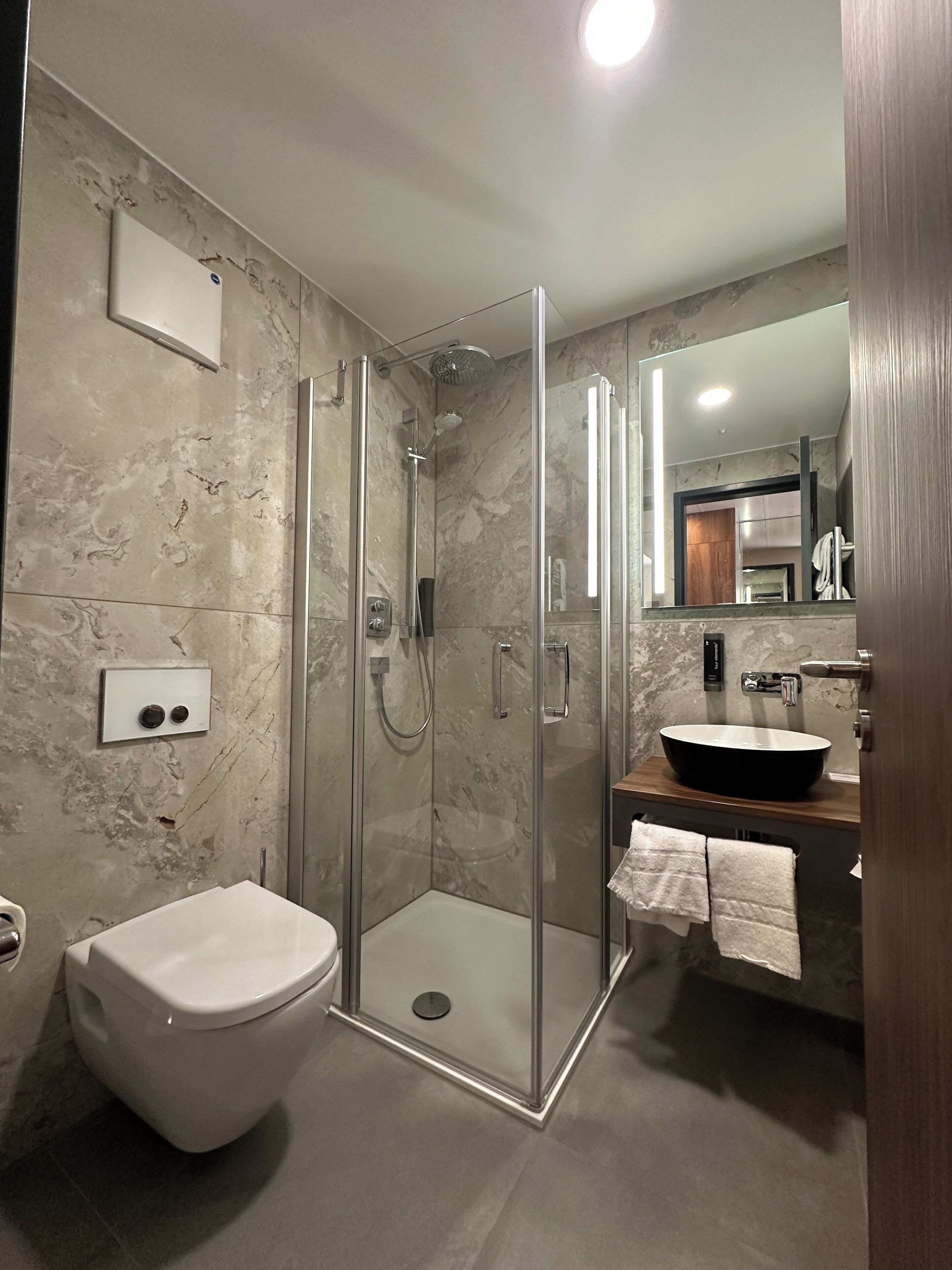 Une salle de bain moderne avec une douche à parois de verre, des toilettes et un lavabo doté d’un grand bac.