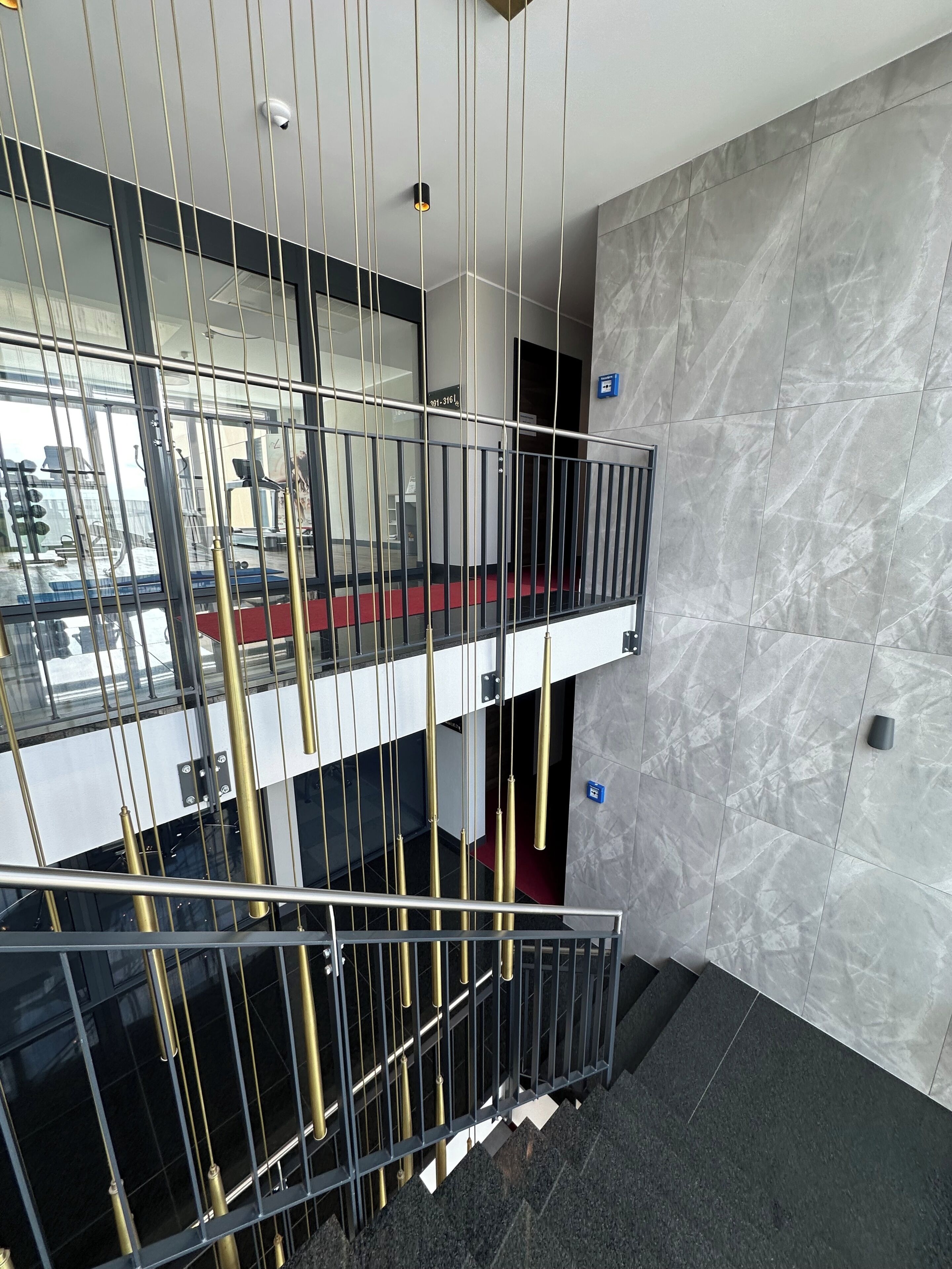 A modern interior with a glass railing, a marble wall, and a visible phone number on the wall.